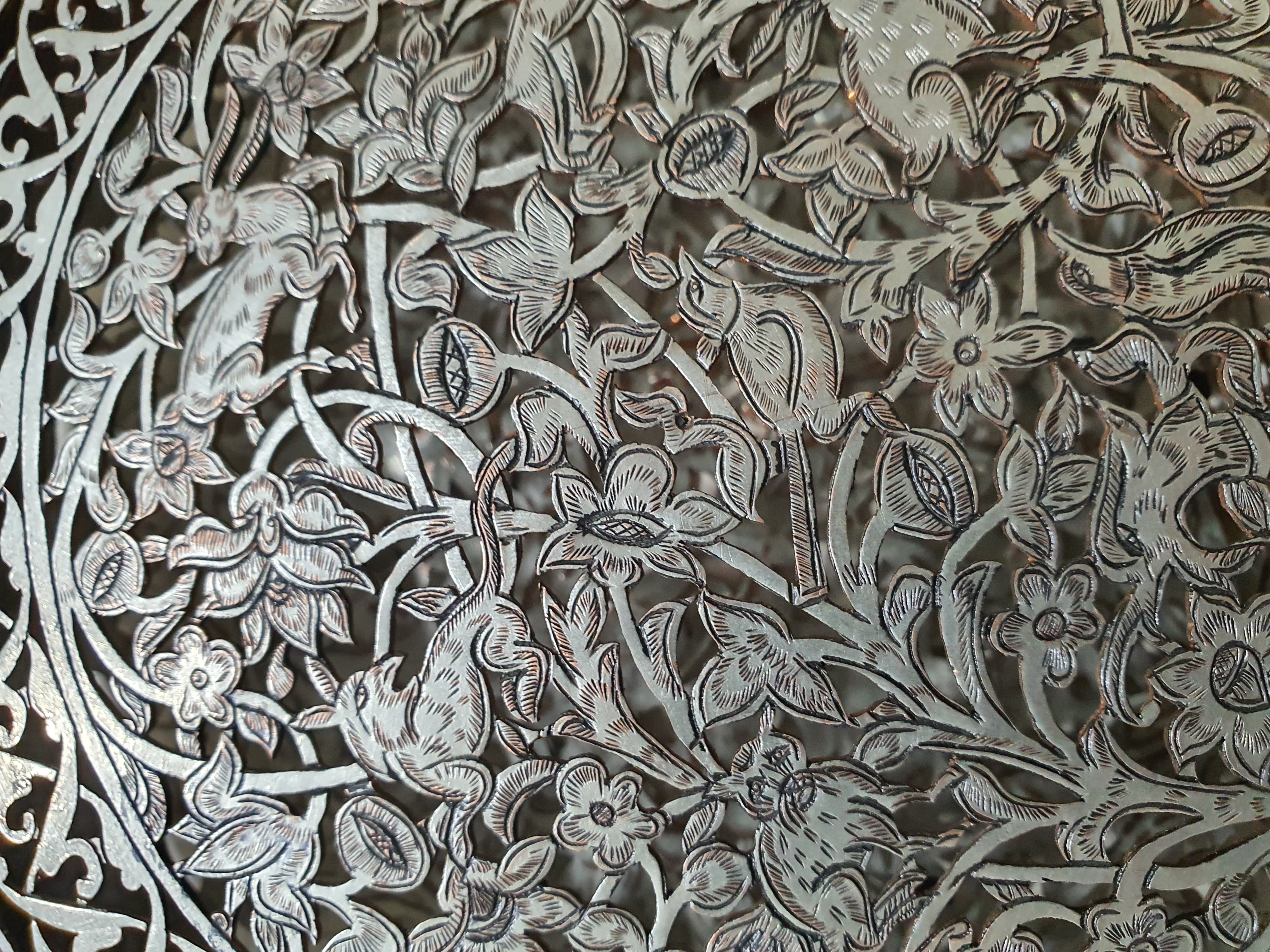 در مرکز قلمزنیهای بسیار زیبا از گل و گیاه و پرنده